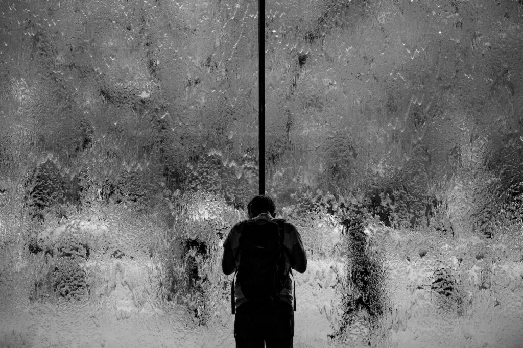 man standing on glass wall with pouring water
